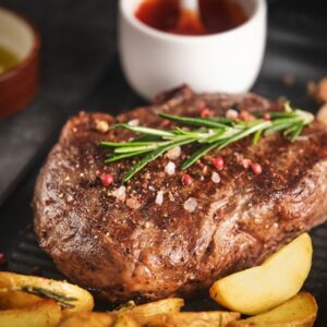 Juisy new york strip steak with rosemary, garlic and potato on skillet pan.