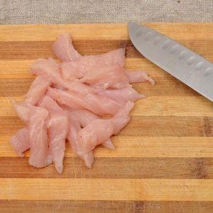 Cutted chicken fillet with knife on a wooden chopping board, ski