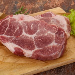 Raw pork steak over wooden board