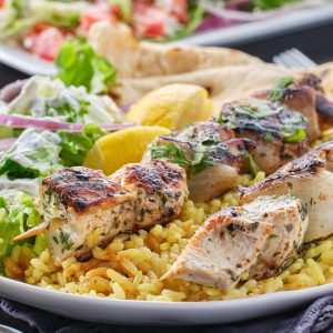 greek chicken souvlaki platter with pita bread, salad and rice